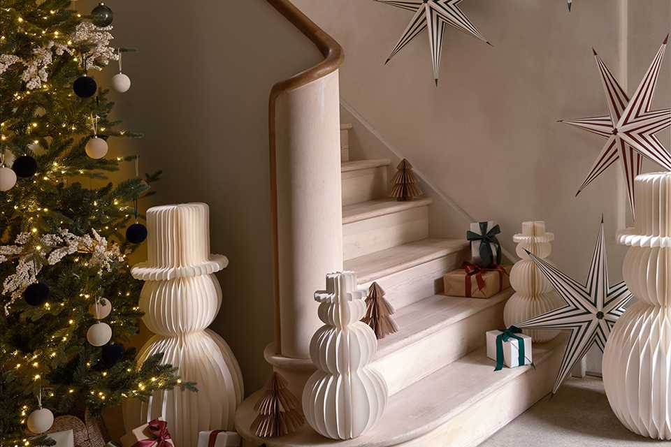 A living room decorated for Christmas with a tree, snowmen, a star and some gifts.