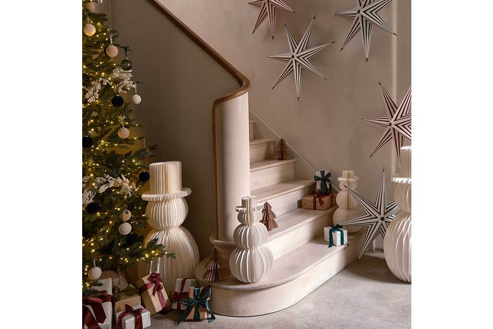 Image of a set of stairs surrounded by paper Christmas decorations with a white colour scheme