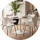 A white round dining table next to matching chairs.