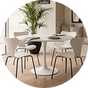 A white round dining table next to matching chairs.