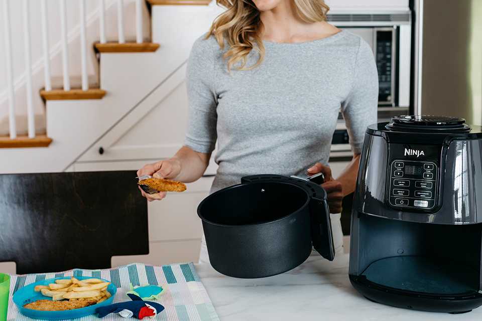 A woman cooking using a Ninja 3.8L Air Fryer and Dehydrator.