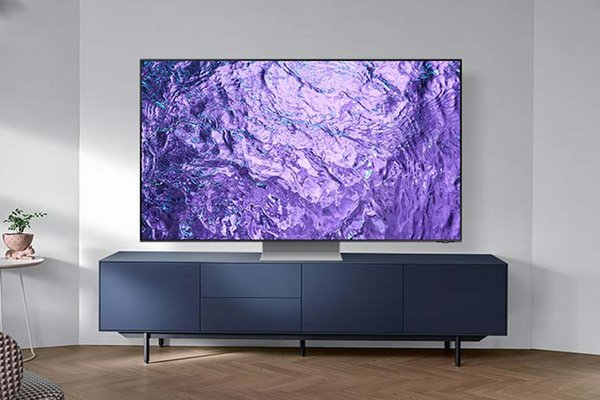 A Samsung QN700C 8K Neo QLED TV placed on a tv stand in a brightly lit living room.