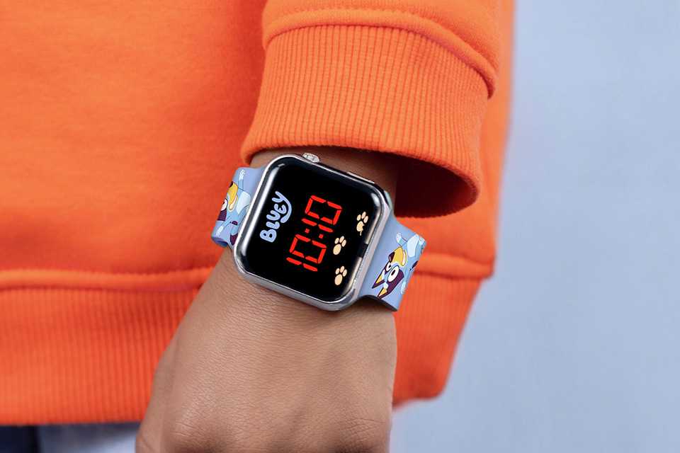 A young boy wearing a digital watch with a Bluey printed strap.