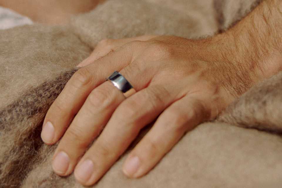 A person wearing an Oura Ring 4 bluetooth silver smart ring.