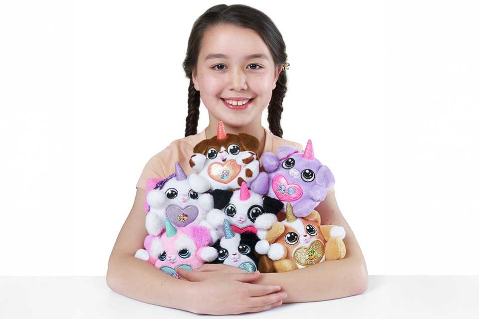 A child with an armful of ZURU Rainbocorns Sparkle Heart Surprise Series 3 Puppycorns.