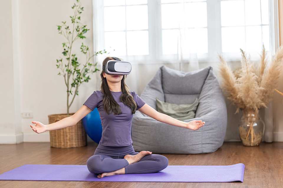 A woman using VR headset to do yoga.