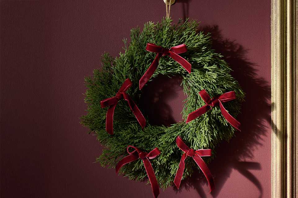 A wreath with red bows hung on a door.