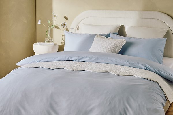 A bed made with a Habitat pale blue bedding set and matching pillows.