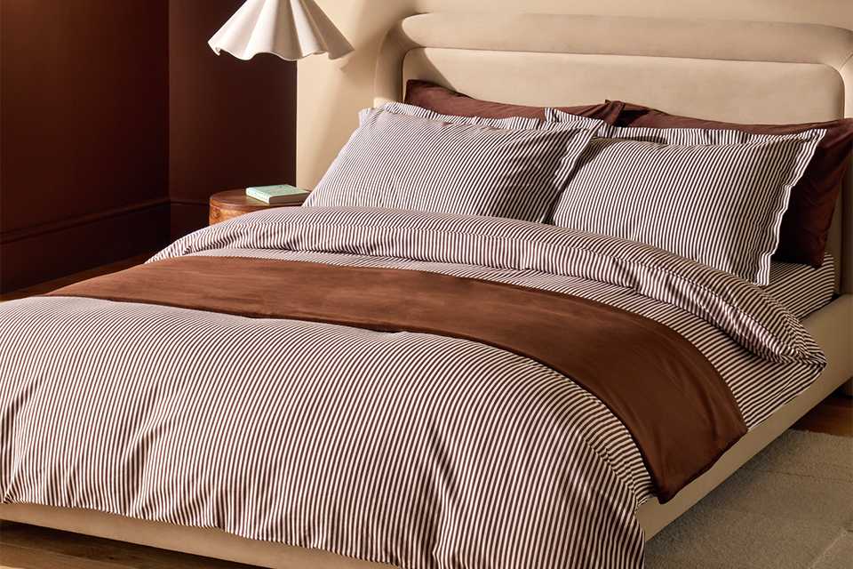 A bed made with a Habitat cotton Oxford edge super king size bedding set.