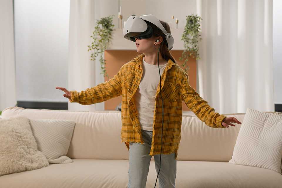 A girl using a Sony PS VR2 headset in a living room.
