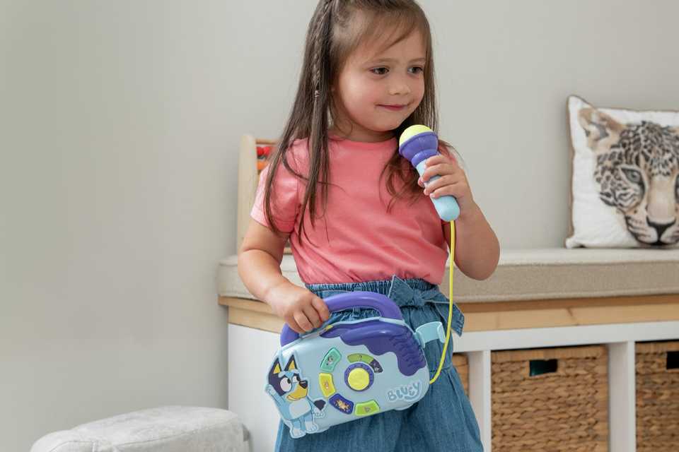 A girl singing using a Bluey boombox.