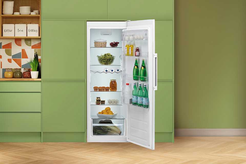 A Hotpoint white fridge seamlessly built into modern green kitchen cabinets.
