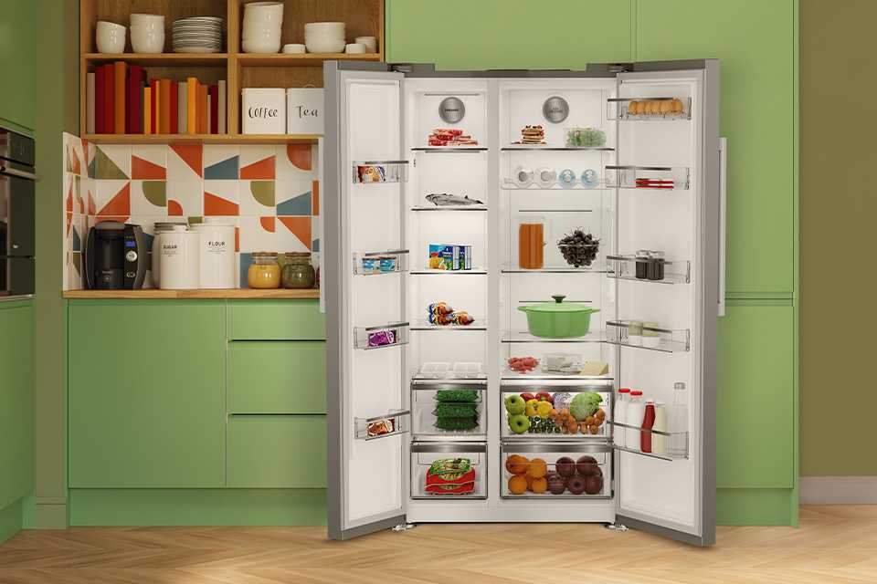 A Hotpoint white double door fridge freezer built into modern green kitchen cabinets.