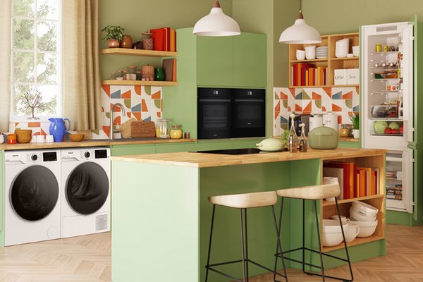 Modern green kitchen with a range of Hotpoint appliances such as washing machine, oven, and fridge.