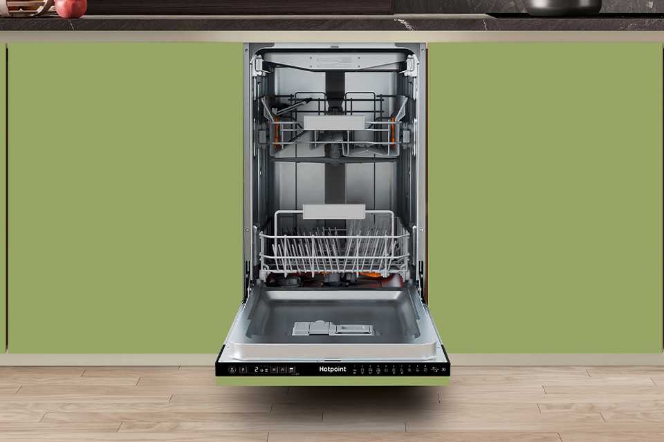 A Hotpoint slim dishwasher seamlessly built into modern green kitchen cabinets.