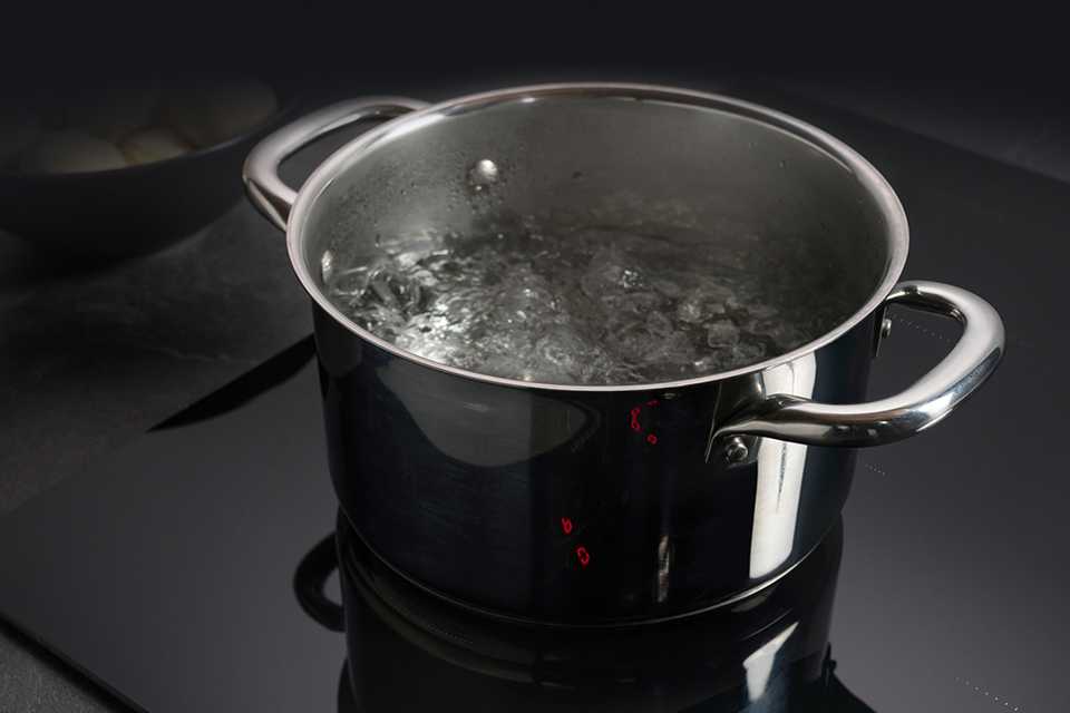 A pot of boiling water on a hob.