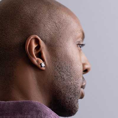 A man wearing Revere Men's Cubic Zirconia Square Stud Earrings.