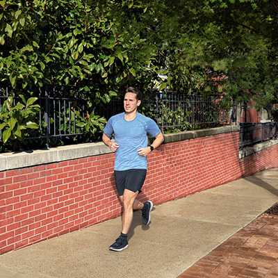 A man wearing a black Garmin Forerunner 55 GPS Running Smart Watch while running.