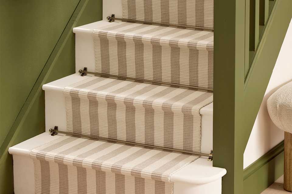 Habitat antique brass stair rods placed over a stair runner on some stairs.