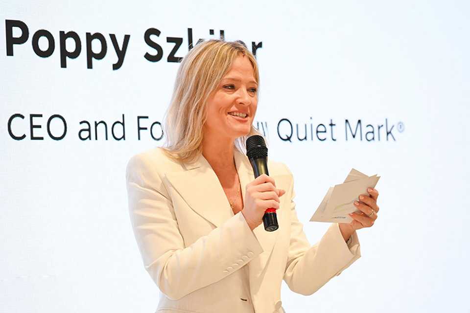 Poppy Szkiler, CEO and founder of Quiet Mark, speaking into a mic at an event.