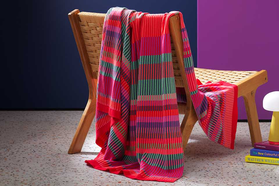 Margo Selby throw draped over wicker chair in purble and blue room.