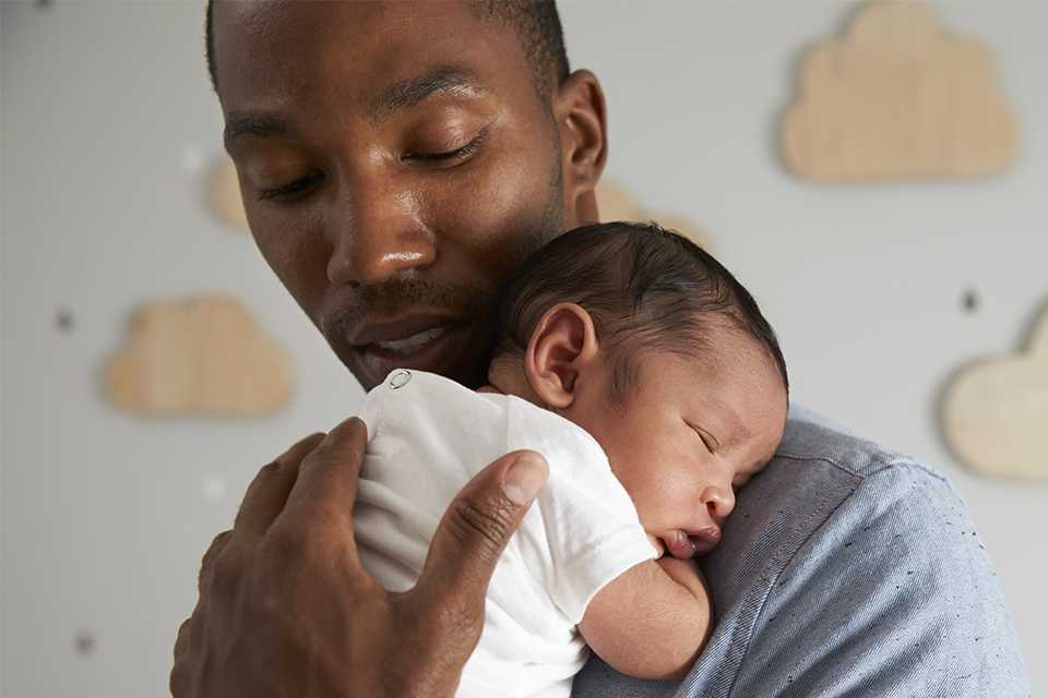 A father holding his newborn baby in a nursery.