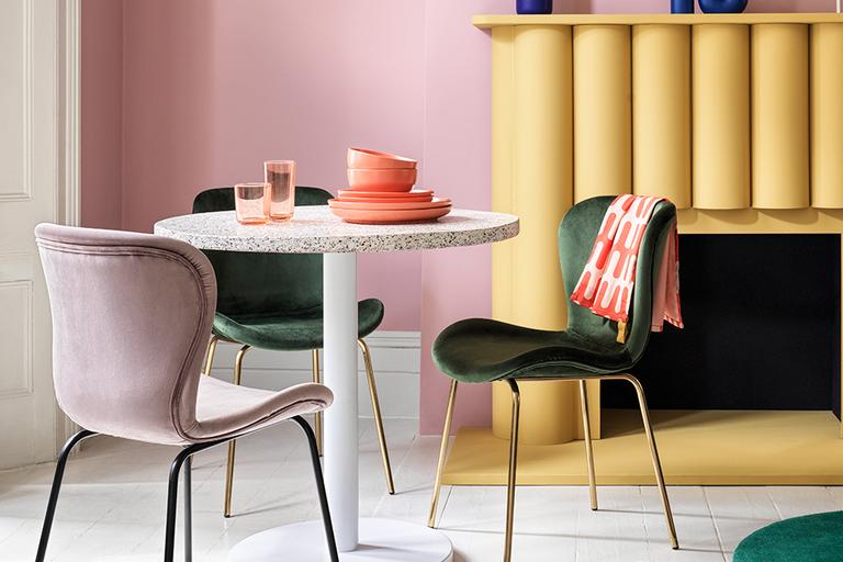 Terrazzo dining table with green and pink velvet chairs.