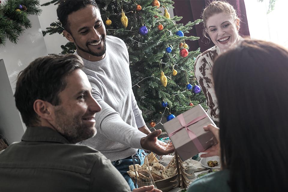 Adults giving Christmas presents around the tree.