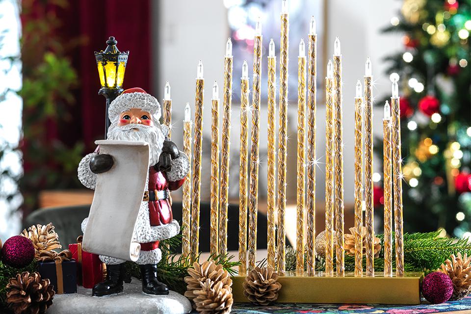 A novelty Father Christmas figure next to some Christmas candles.