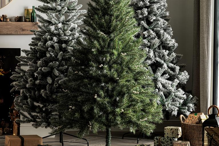 A beautifully lit Christmas tree with a star tree topper and gifts underneath in a lounge.