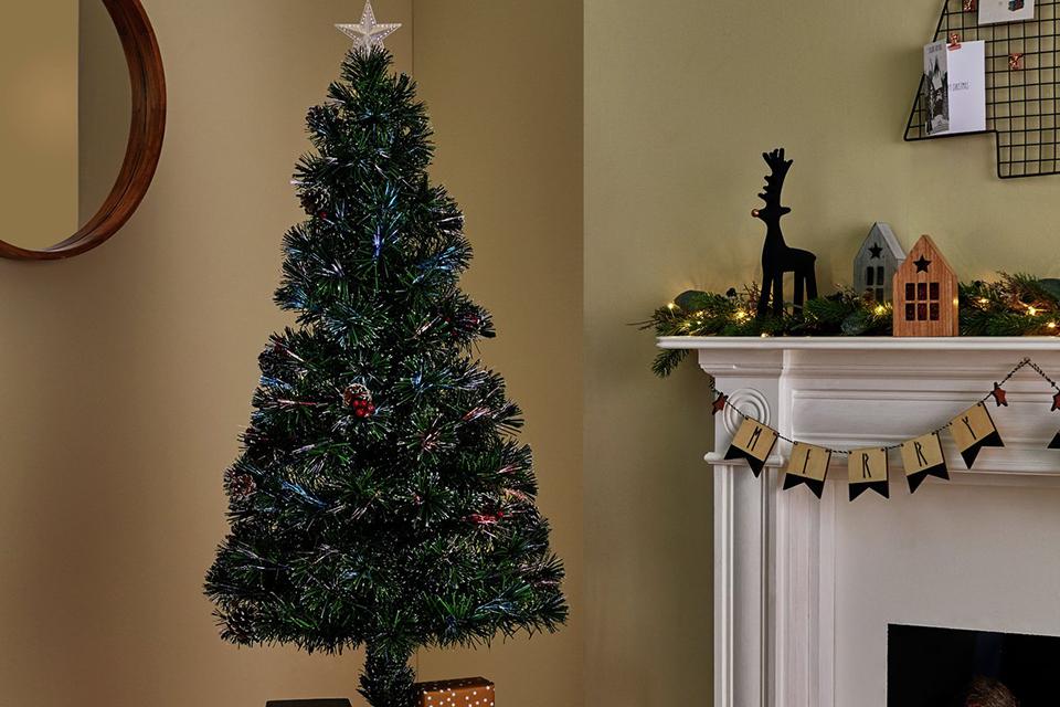 A fibre optic pre-lit Christmas tree placed next to a side table.