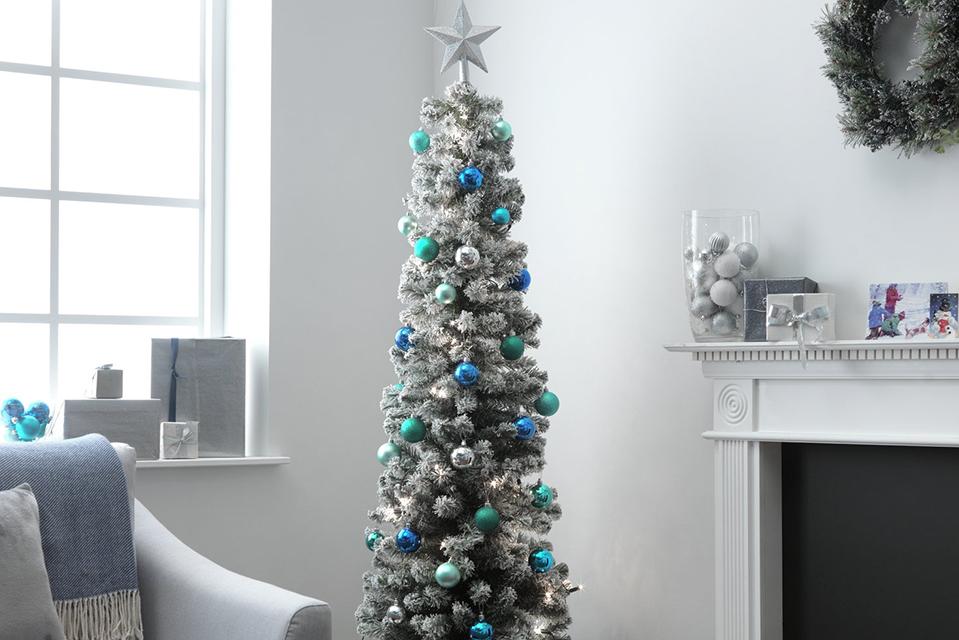 A 6 foot snow-tipped pencil Christmas tree with presents underneath.