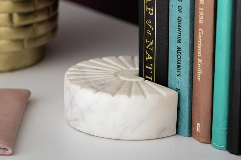 Books on slef with book stand and gold vase.