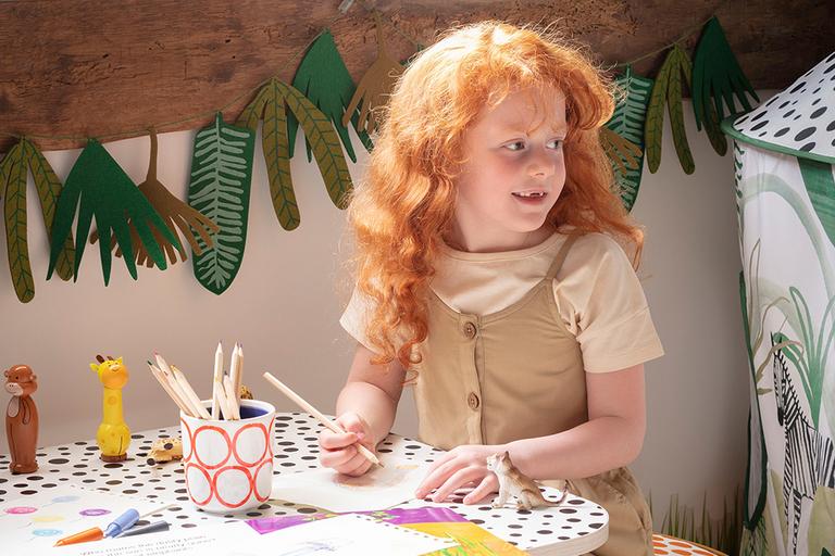 Young child drawing picture on craft table.