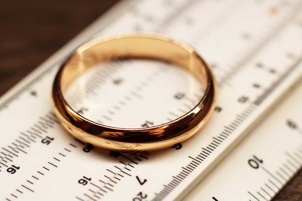 A gold wedding band placed on ring measuring scale.