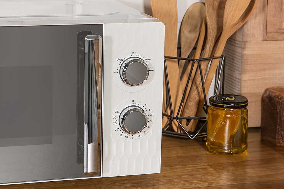 Russell Hobbs white microwave on wooden kitchen countertop with other things.