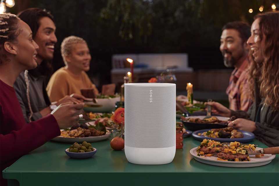 People seated around adining table with a white Sonos Move 2 speaker kept in the middle.