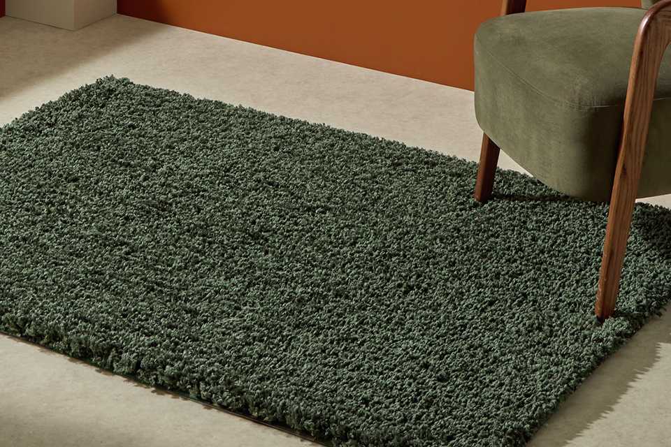 A Habitat olive rug under a chair in a living room.