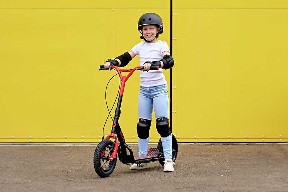 A girl posing with a Zinc Radikal 12 inch Big Wheel BMX Scooter.