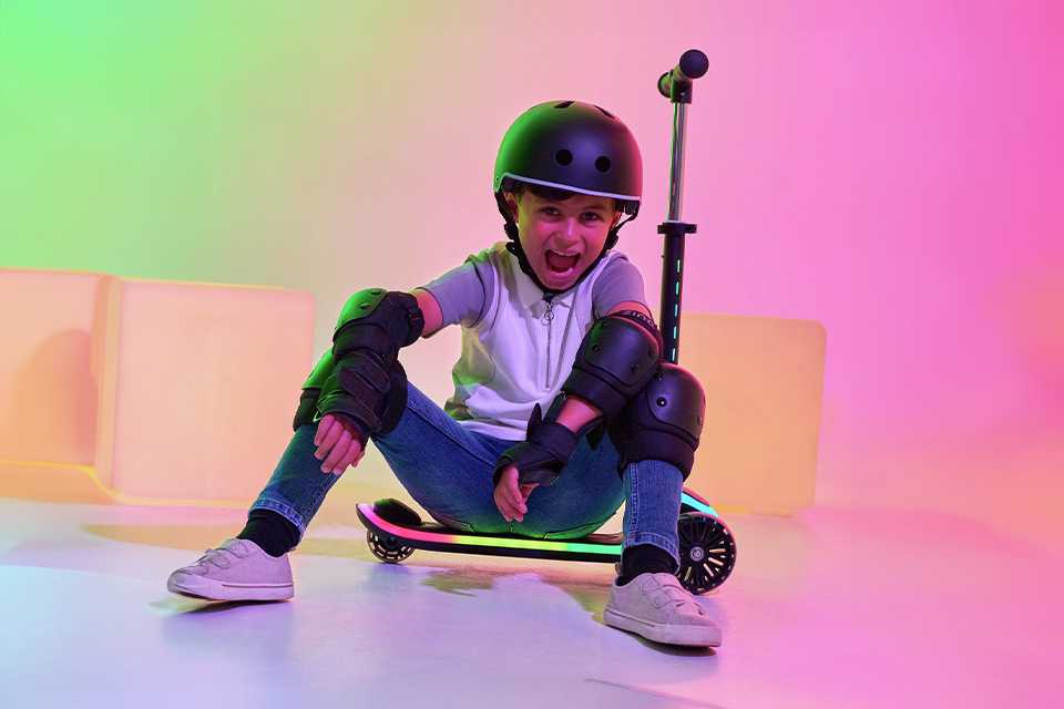 A boy sitting on a Zinc Sunshine Light Up 3 wheel scooter in black colour.