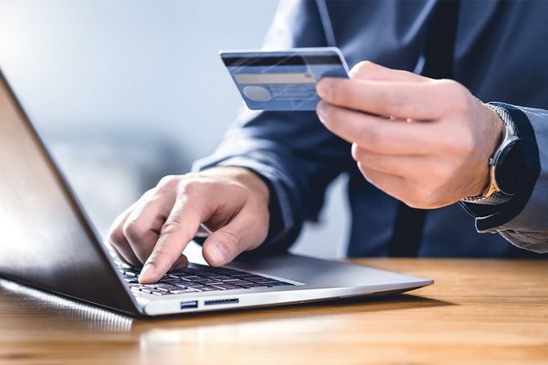A person entering credit card details on a website using a laptop.