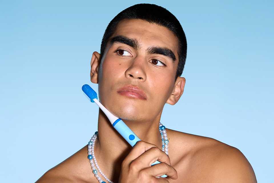 A man holding a blue Ordo Sonic Edge toothbrush.