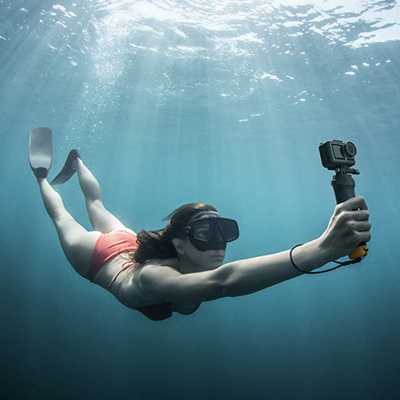 A woman in swimsuit using a GoPro camera underwater.