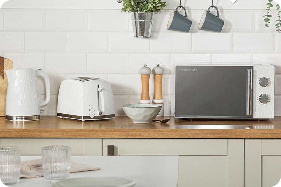 A kettle, toaster and a microwave on a kitchen counter top.