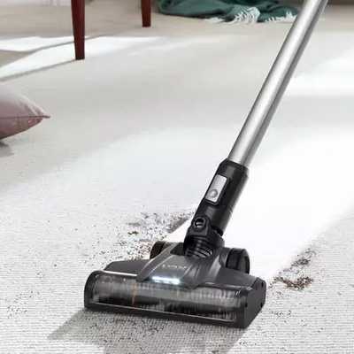 A man using Vax Blade 4 Classic Cordless Vacuum Cleaner to clean under a sideboard.