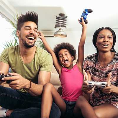 A young girl playing games on her gaming console with her parents.