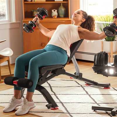 A woman using BowFlex 5.1S Stowable Bench to workout at home.