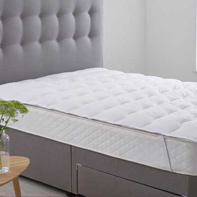 Mattress topper on mattress in bedroom.