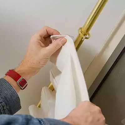 Person putting up curtains on a curtain pole.