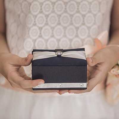 A woman in a wedding gown holding a gift box.